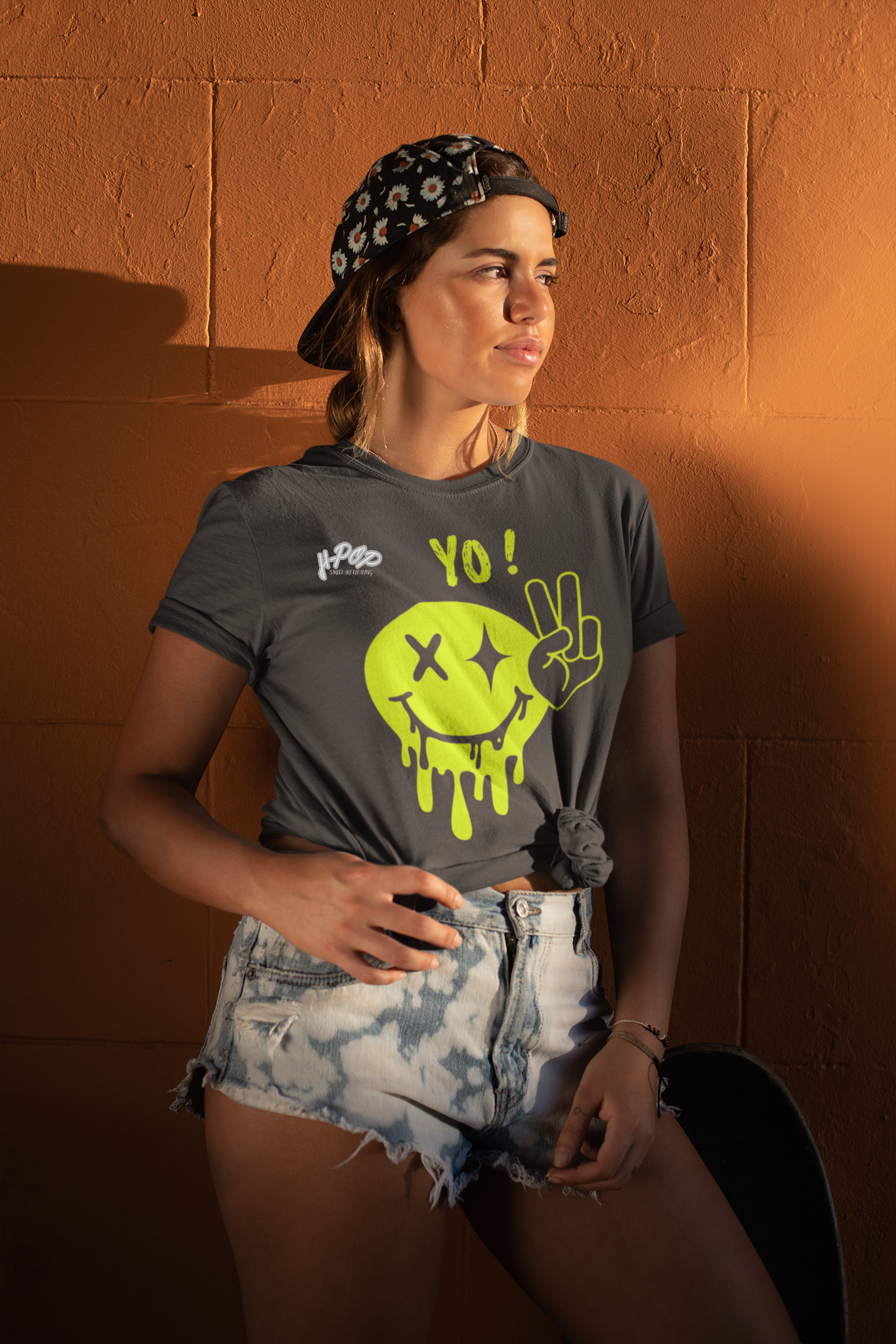 Ragazza con t-shirt streetwear grafica ispirata alla street art e ai graffiti, stile urbano e ribelle sotto la luce del tramonto.