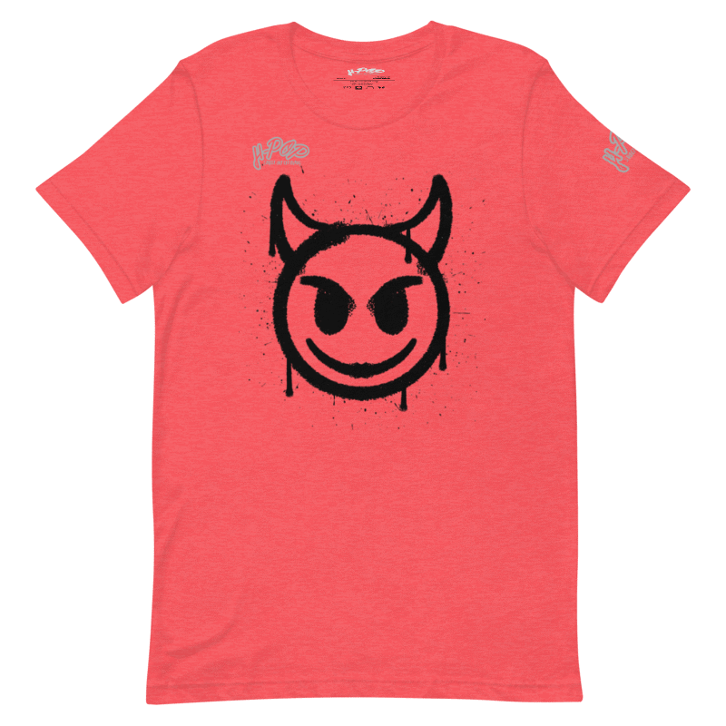 T-shirt color corallo/rosa salmone con una stampa grafica centrale di una faccina sorridente stilizzata con corna da diavoletto, realizzata con un effetto spray o graffiti in nero. Il design ha un'estetica underground e urbana. L'immagine è presentata su uno sfondo trasparente.