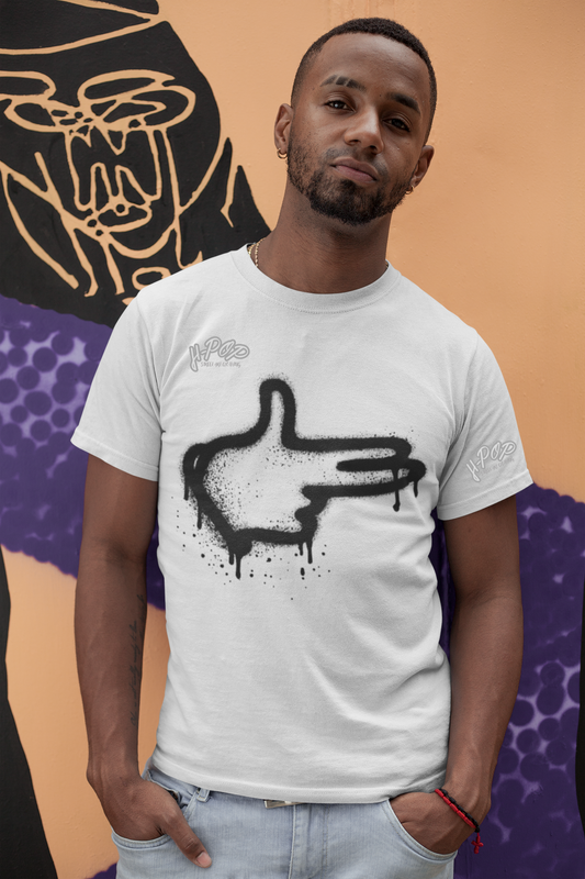 Uomo con t-shirt bianca dallo stile urban, con grafica a spray raffigurante una mano stilizzata tipo "click" o "puntatore", davanti a un murales di street art. Moda streetwear, arte urbana, stile hip hop, abbigliamento casual, t-shirt grafiche.