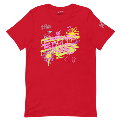 T-shirt rossa con una stampa grafica vibrante e in stile graffiti al centro. La stampa presenta scritte stilizzate e simboli come stelle, corone, cuori e fiori, in colori neon come il giallo lime, il rosa e il viola, con schizzi di vernice. Il design ha un'estetica urbana e vivace. L'immagine è presentata su uno sfondo trasparente.