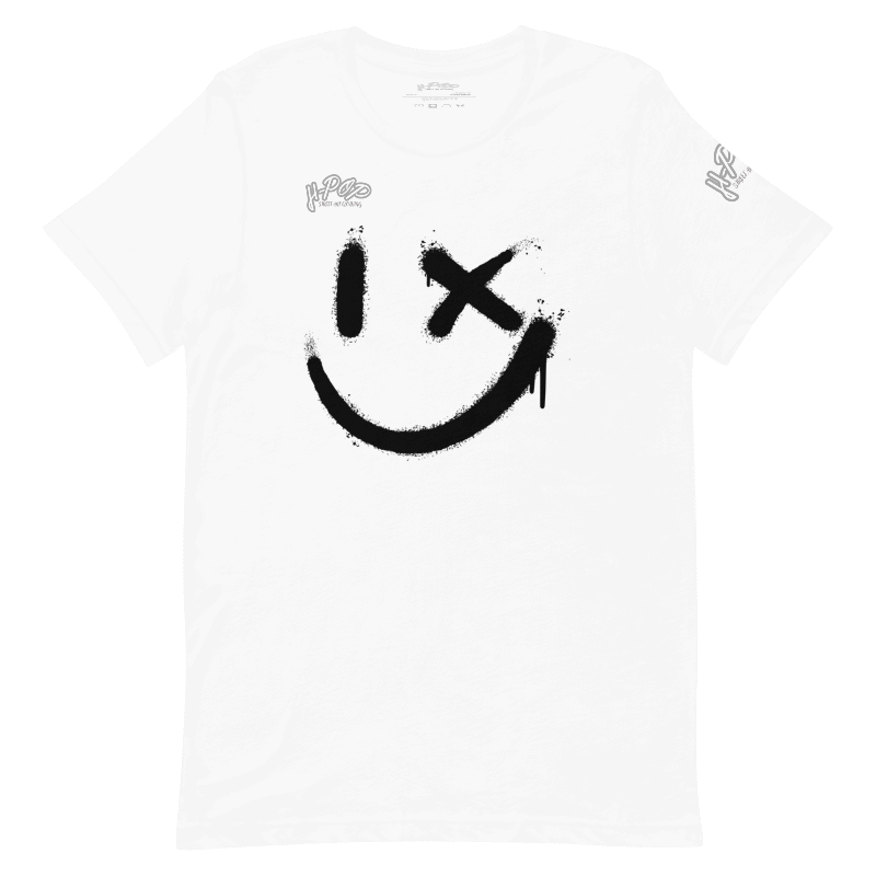 Una maglietta bianca con una grande stampa nera di uno smiley stilizzato: un occhio è un tratto verticale e l'altro una "X", con un effetto vernice spray e gocciolante. La maglietta ha anche il logo "H-Pop" in alto a sinistra e sulla manica.