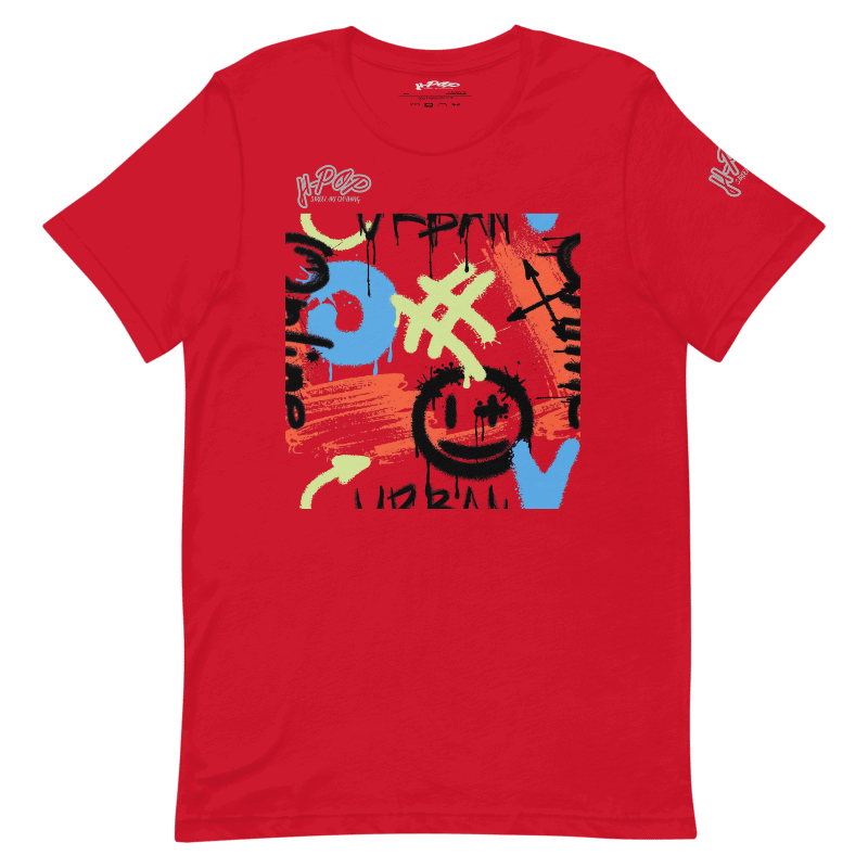 T-shirt rossa con una vivace stampa grafica in stile graffiti al centro. Il design include tratti di pennello, simboli e testo stilizzato in colori come blu, arancione, verde lime e nero, con una faccina sorridente stilizzata. L'immagine è presentata su uno sfondo trasparente.