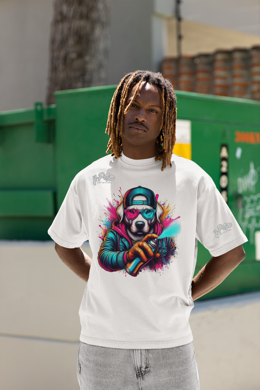Un uomo con i dreadlocks indossa una maglietta bianca oversize con una vivace stampa grafica colorata. La stampa raffigura un cane con un cappello, occhiali da sole rossi e blu, che tiene in mano una bomboletta spray con schizzi di colore. L'uomo è in piedi con le mani ai fianchi, con uno sguardo sicuro e posa davanti a un cassonetto verde.
