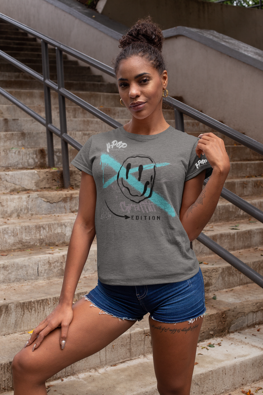 Ragazza con maglietta grigia T-shirt casual con stampa di faccina sorridente stilizzata e design geometrico, abbinata a shorts di jeans. Look estivo, abbigliamento femminile, moda urbana, t-shirt grafica.