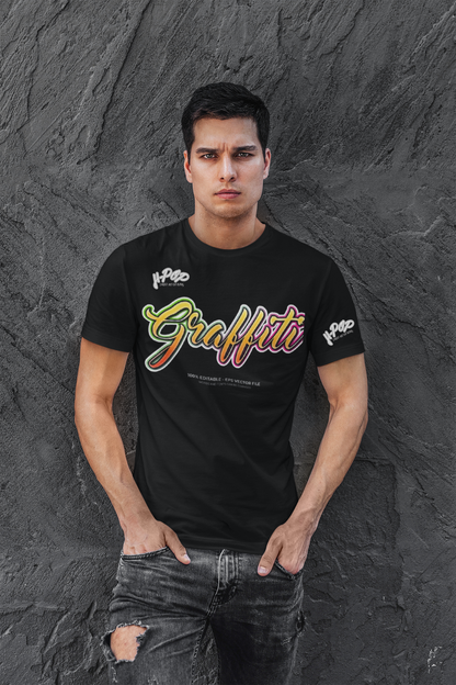 Un giovane uomo con un'espressione seria indossa una t-shirt nera con la scritta "Graffiti" in stile calligrafico dai colori vivaci e sfumati (giallo, arancione, rosso, rosa). Indossa jeans scuri strappati e tiene le mani nelle tasche, posando contro un muro scuro con una texture rocciosa o irregolare.