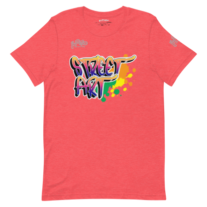 T-shirt color corallo/rosa salmone con una stampa grafica centrale che recita "STREET ART" in stile graffiti, con lettere dai colori sfumati (arancione, viola, verde) e schizzi di vernice colorati. Il design ha un'estetica urbana e vivace. L'immagine è presentata su uno sfondo trasparente.