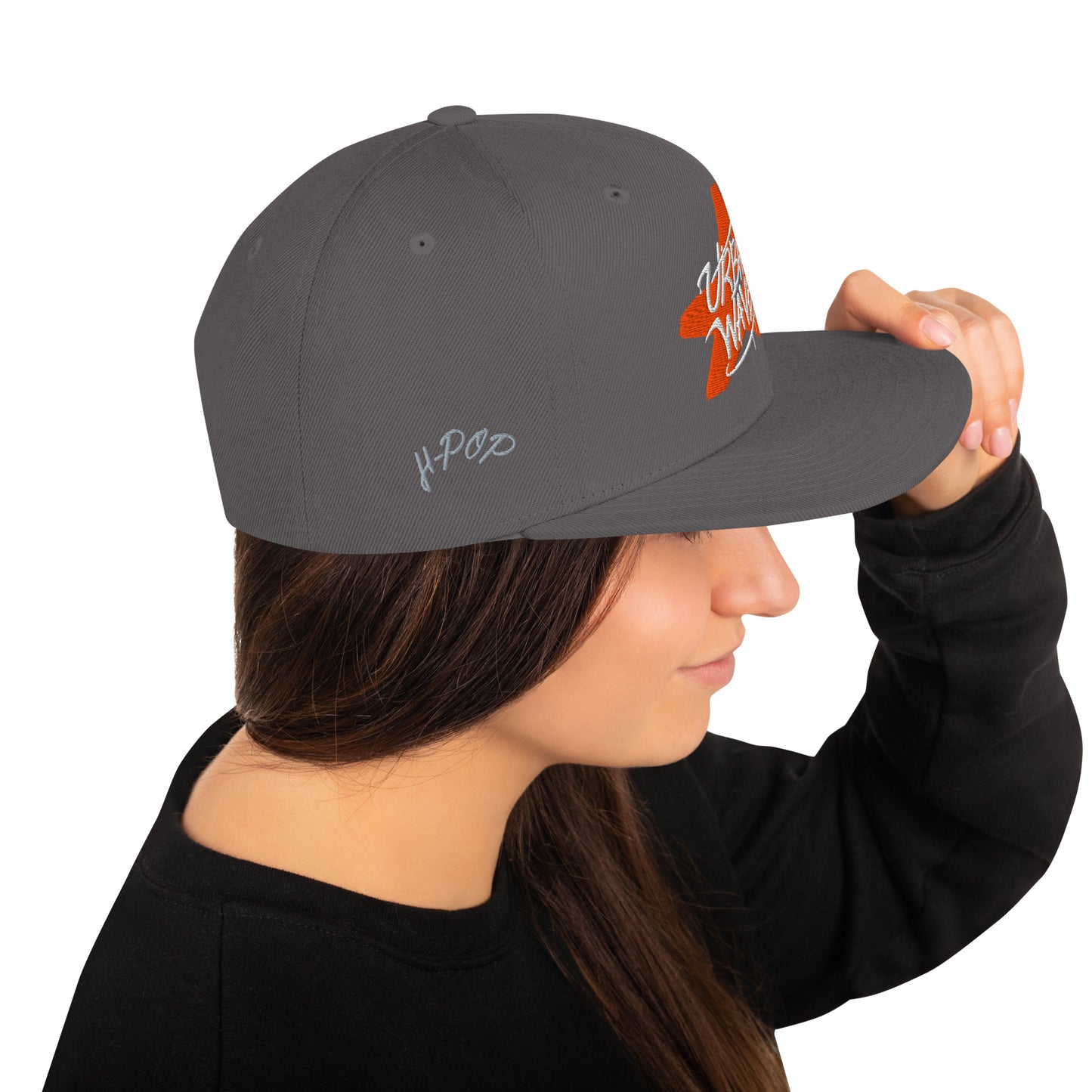 Profilo di donna che indossa un cappello snapback grigio con logo frontale arancione 'Urban Waves' a forma di stella e piccolo logo laterale grigio. Perfetto per abbigliamento streetwear e moda giovanile. Scopri i nostri cappelli personalizzabili di alta qualità.