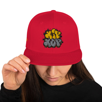 Persona che tiene un cappello snapback rosso con un logo 'Hip Hop' in stile graffiti giallo e grigio. Ideale per la moda streetwear, la cultura hip hop e gli accessori urbani di tendenza. Cappellino unisex con visiera piatta.